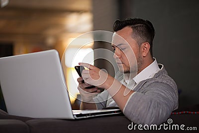 Man using laptop and phone in office Stock Photo