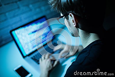 Man using laptop writing programming code on laptop. Young hacker work on laptop in the night Stock Photo