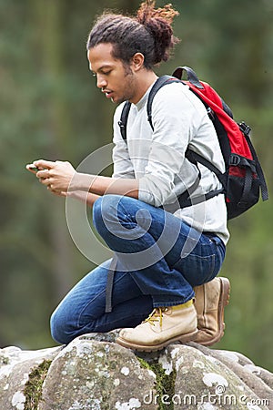 Man Using Mobile Phone Whilst Hiking In Countryside Stock Photo