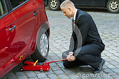 Man using red hydraulic floor jack for car repairing Stock Photo