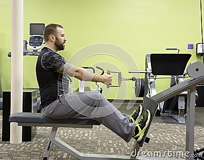Man Using Seated Row Machine Stock Photo