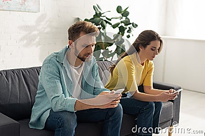 Man using smartphone near girlfriend chatting Stock Photo