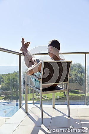 Man using a smartphone and sunbathing in a chair Stock Photo