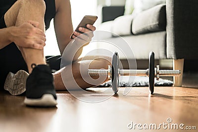 Man using smartphone during workout at home Stock Photo