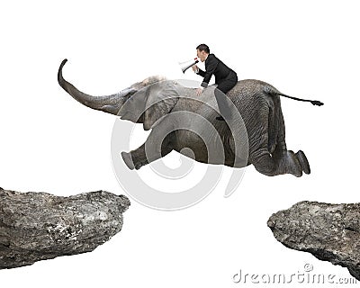 Man with using speaker riding elephant flying over two cliffs Stock Photo