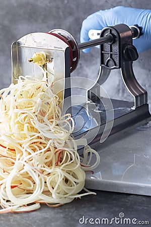 Man using spiralizer to cut apple into strips. Stock Photo