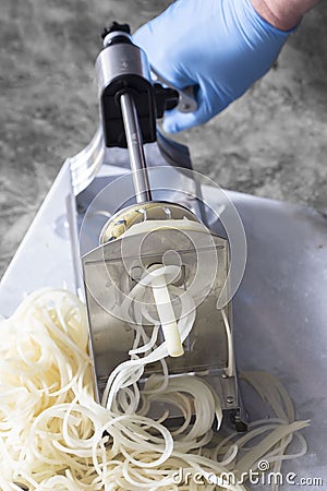 Man using spiralizer to cut potato into strips. Stock Photo