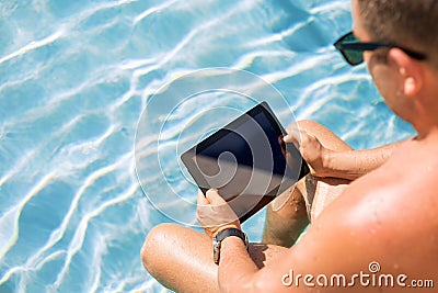 Man using tablet computer by the pool Stock Photo