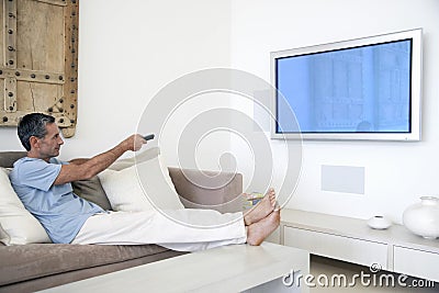 Man Using TV Remote In Living Room Stock Photo