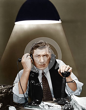 Man using two telephones Stock Photo