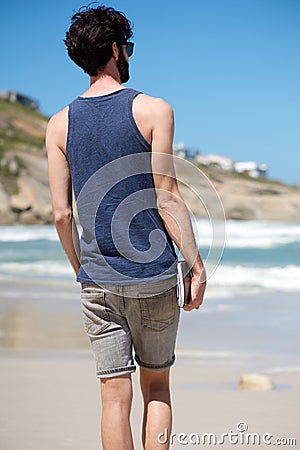 Man on vacation walking alone on beach with book Stock Photo