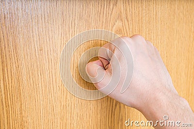 Man (the visitor) is knocking on closed wooden door Stock Photo