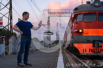 A man with vitiligo at the train station with a phone next to the train Stock Photo