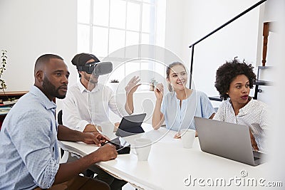 Man in VR goggles at a desk with colleagues in an office Stock Photo