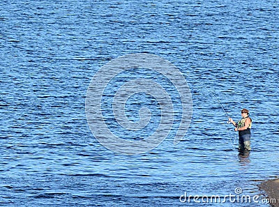 A man in waders fishing from in the water. Editorial Stock Photo