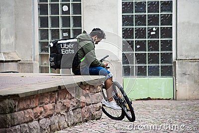 Man waiting in the street with an uber eats backpack and bicycle Editorial Stock Photo