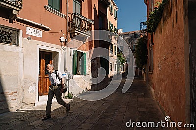Man is walking along the narrow and bright streets of sunny Venice, Italy Editorial Stock Photo