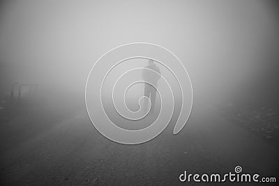 Man walking away on misty road. Man standing alone on rural foggy and misty asphalt road Stock Photo