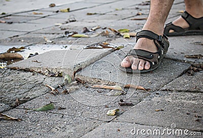 Man walking on broken dangerous cracked sidewalk. Broken concrete pathway brick surface background, close up abstract cracked Stock Photo