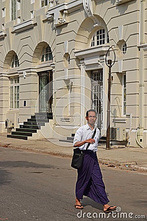 A man walking down the street in Yangon wearing traditional Burmese longyi Editorial Stock Photo