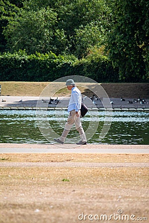 Man walking next to a pond in Hyde Park in London, vertical Editorial Stock Photo