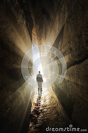 Man walking out of a cave into the light Stock Photo