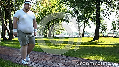 Man walking slowly, exhausted after running, cardio training for weight loss Stock Photo