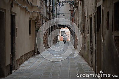 A man walking a a Venetian street. Streets of Venice, Italy Editorial Stock Photo