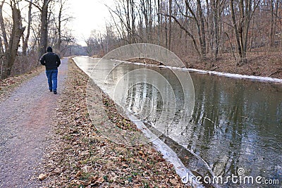 Man walks along frozen canal aside Delaware River Stock Photo