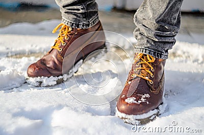 Man walks in the snow. Feet shod in brown winter boots. Stock Photo