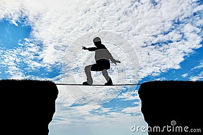 Man walks on a tightrope over a cliff Stock Photo