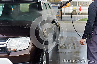 A man washes a brown car, a man washes a car at a contactless car wash Editorial Stock Photo