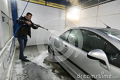 A man washes a car in a box contactless car wash self-service with a water gun in the manual self-service washing Stock Photo