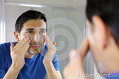 Man washing face with facial cleanser face wash soap looking at mirror in bathroom at home. Men skin care concept Stock Photo