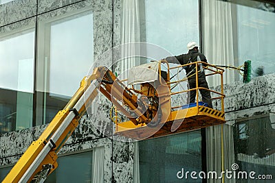 A man washing windows and facade of a building with a mop. Editorial Stock Photo