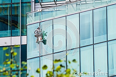 Man washing windows on a glass skyscraper Editorial Stock Photo