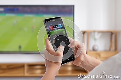 Man watches a soccer match on TV and follows online betting on his phone Stock Photo