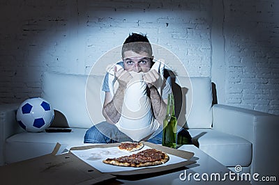 Man watching football game on tv nervous and excited suffering stress on couch Stock Photo