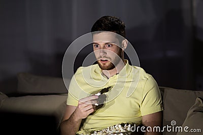 Man watching tv and eating popcorn at night Stock Photo