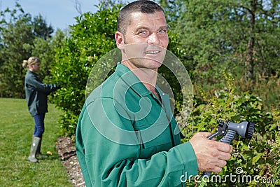 man watering plants with hose Stock Photo