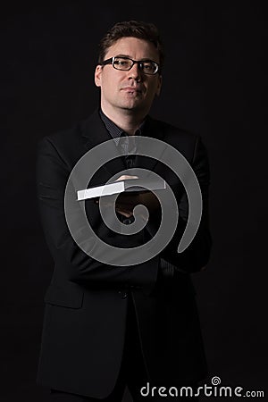 Man wearing a black suit presents a book to read Stock Photo