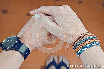 Man wearing a bracelet made of rope, wood, leather, beads and colored rope sack. Black watch on man hand. Hipster Stock Photo