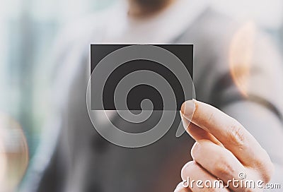 Man wearing casual shirt and showing blank black business card. Blurred background. Ready for private information Stock Photo