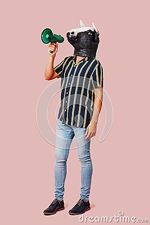 Man wearing a cow mask speaks into a megaphone Stock Photo