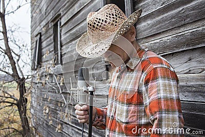 Man wearing cowboy hat holding a microphone. Stock Photo