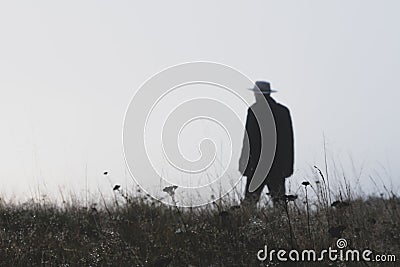 A man wearing a fedora hat standing out of focus on a misty winters day Stock Photo