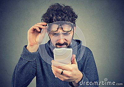 Man wearing glasses having trouble seeing cell phone message Stock Photo