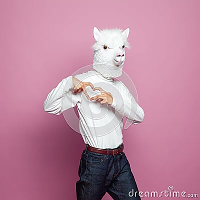 Man wearing lama mask making heart with hands on bright pink background Stock Photo