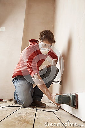 Man Wearing Mask While Sanding Wall Stock Photo