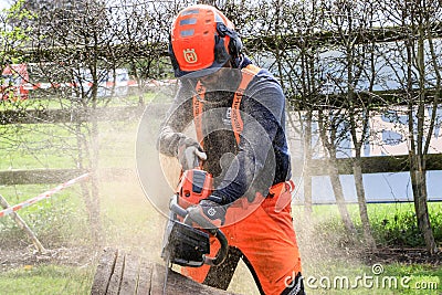 A man sawing wood using electrical chainsaw. Editorial Stock Photo